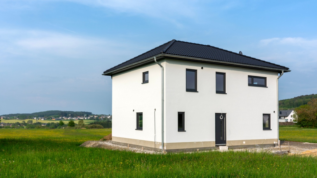 A newly built prefabricated house situated in a green field.