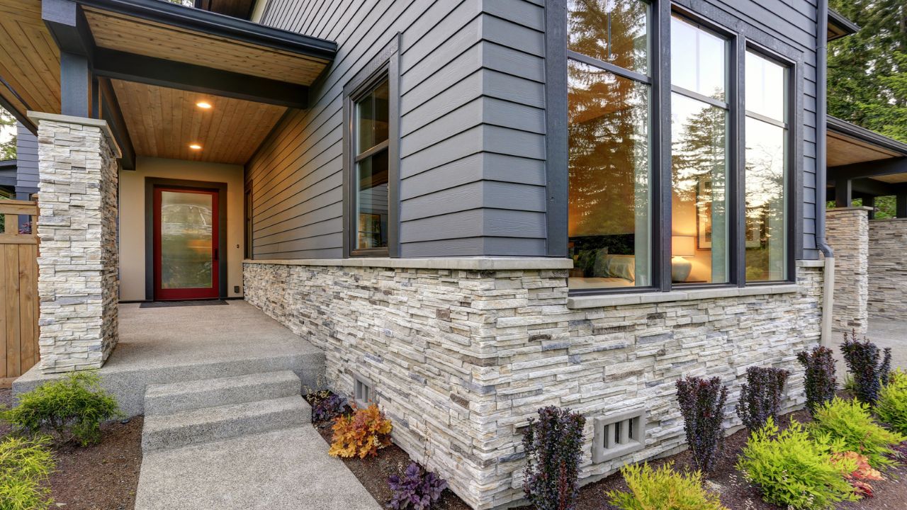 A contemporary home entrance with stone accents and a bold red door, showcasing a blend of materials.