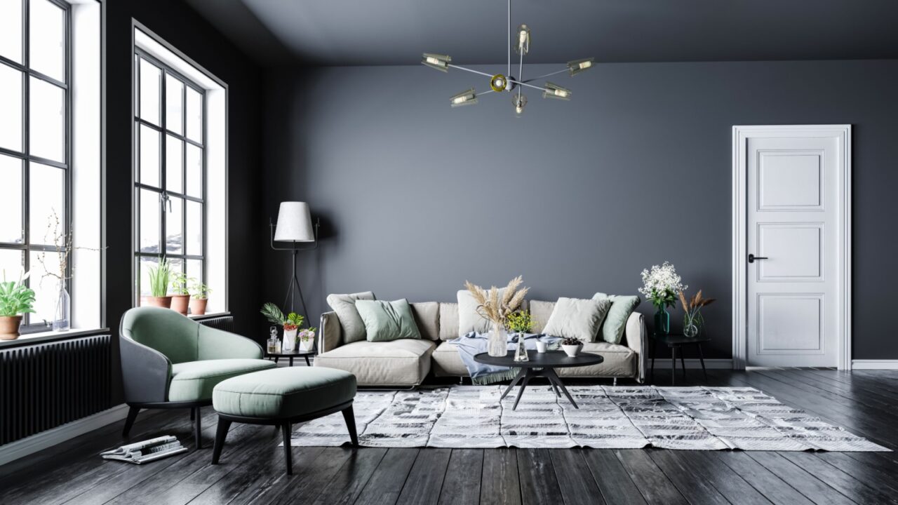A luxurious gray living room interior with sleek pendant, modular sofa, coffee table, side tables, floor lamp, and a mint green armchair with footrest.