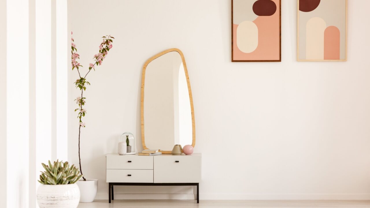 A stylish entryway featuring a minimalist console table, a decorative mirror, and abstract art.