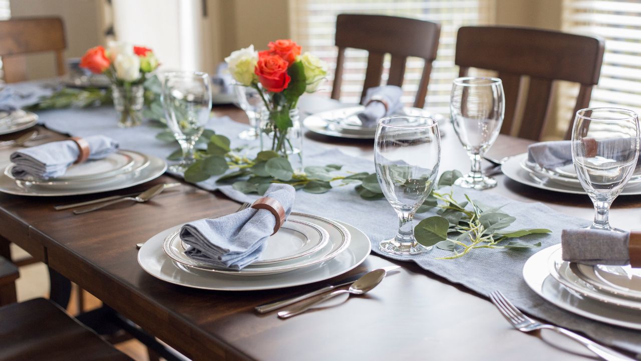 A beautifully set dining table with flowers and tableware.