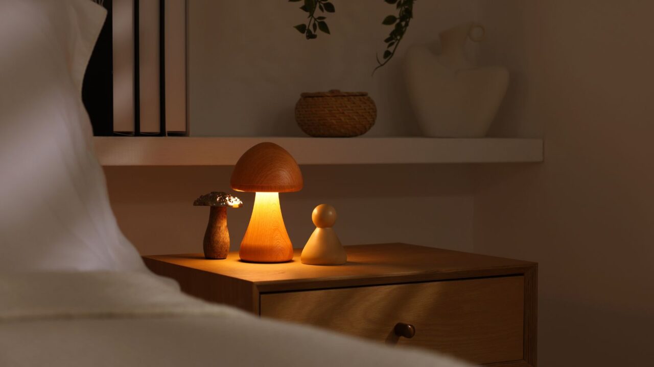 A soft bedside mushroom lamp on a wooden bedside table.