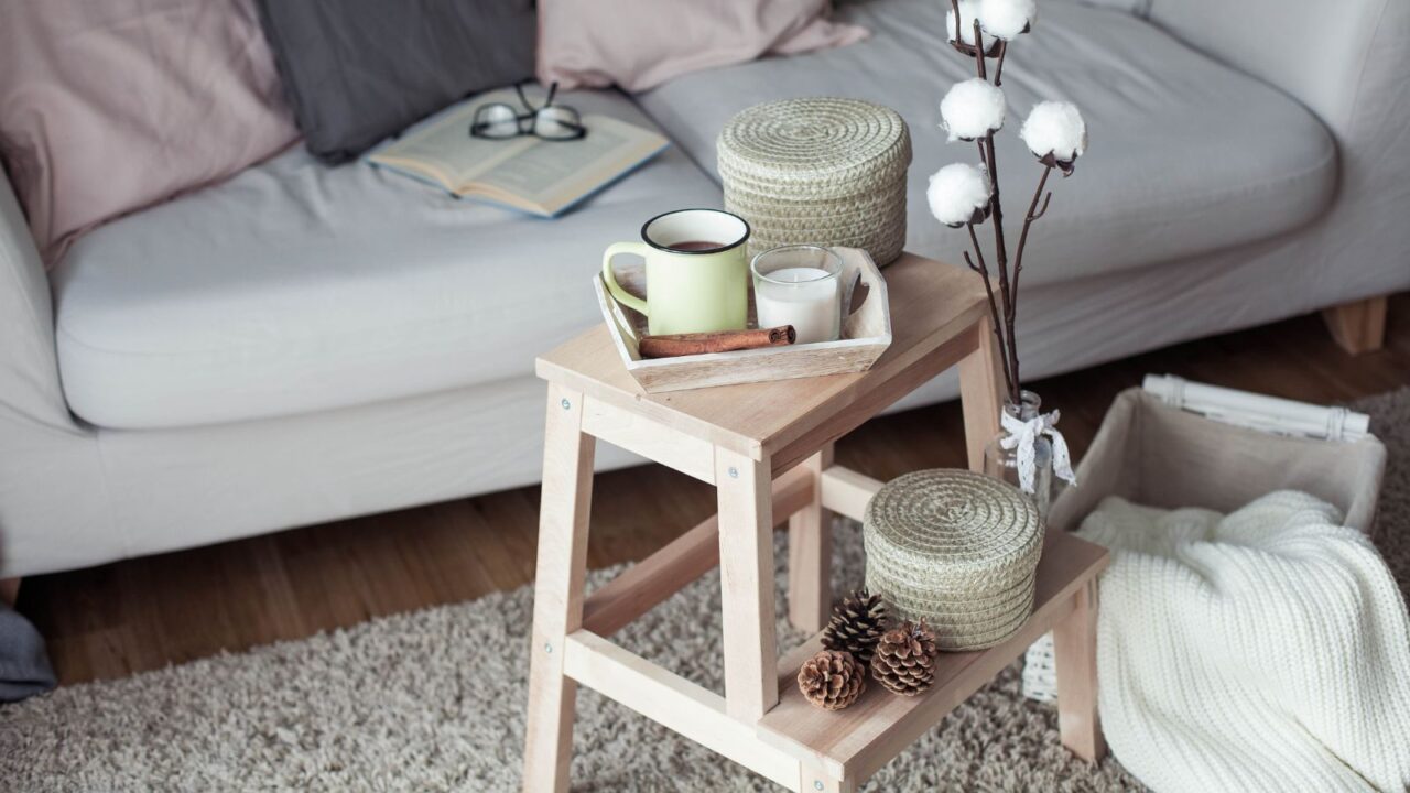 A wooden coffee table on a rug with a gray sofa in the background.