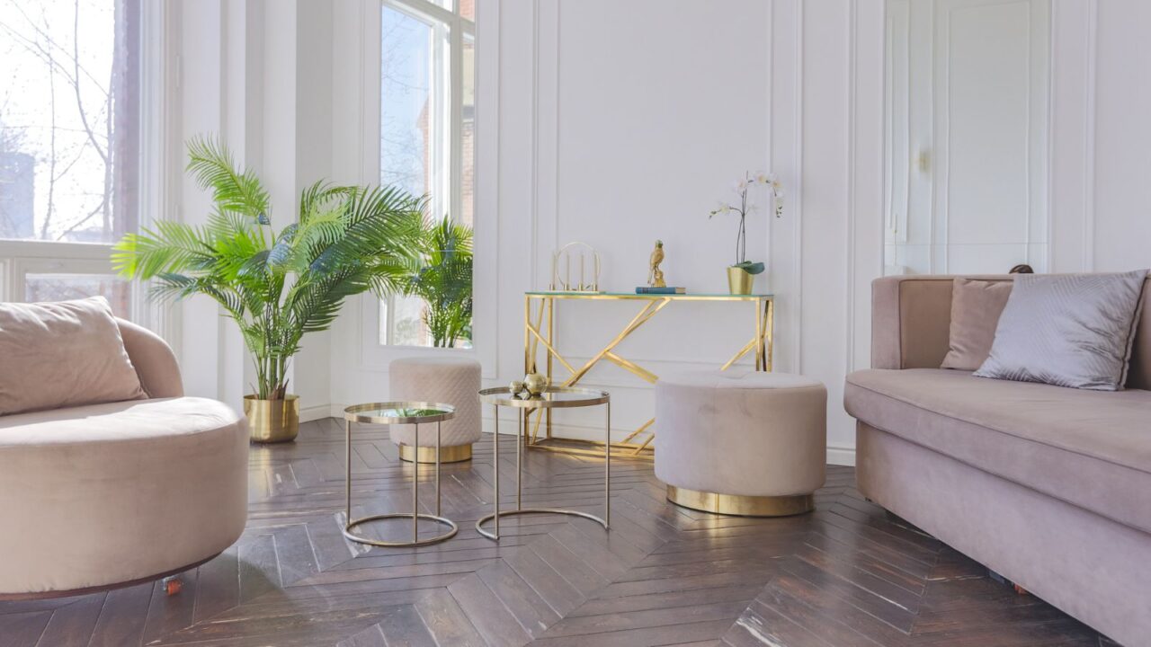 A bright room interior with cozy seating, nesting coffee table, console table, and a decorative plant pot.