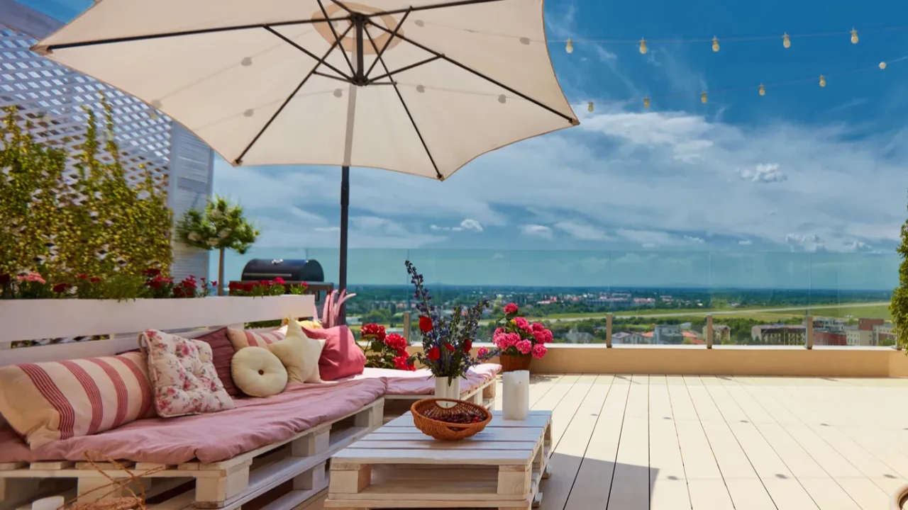 A cozy rooftop patio with wooden pallet furniture and a patio umbrella.