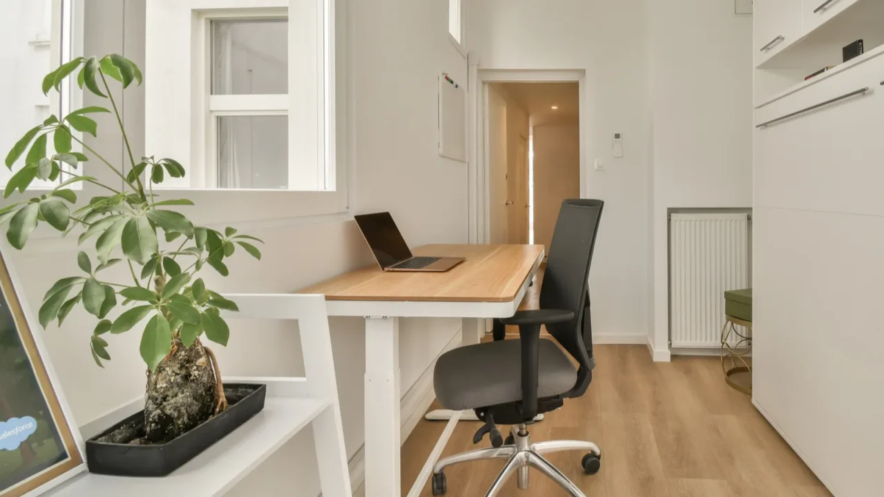 a home office with wood flooring and white walls along