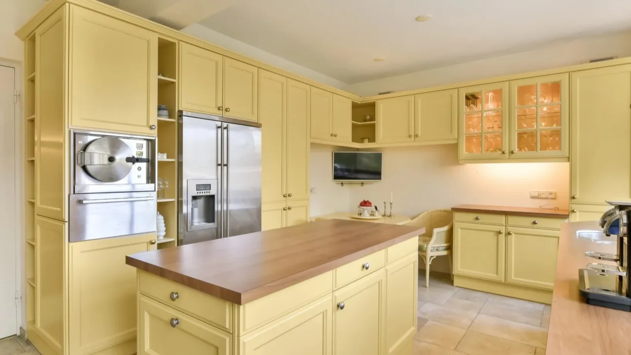 a kitchen with yellow cabinets and wood counter tops in