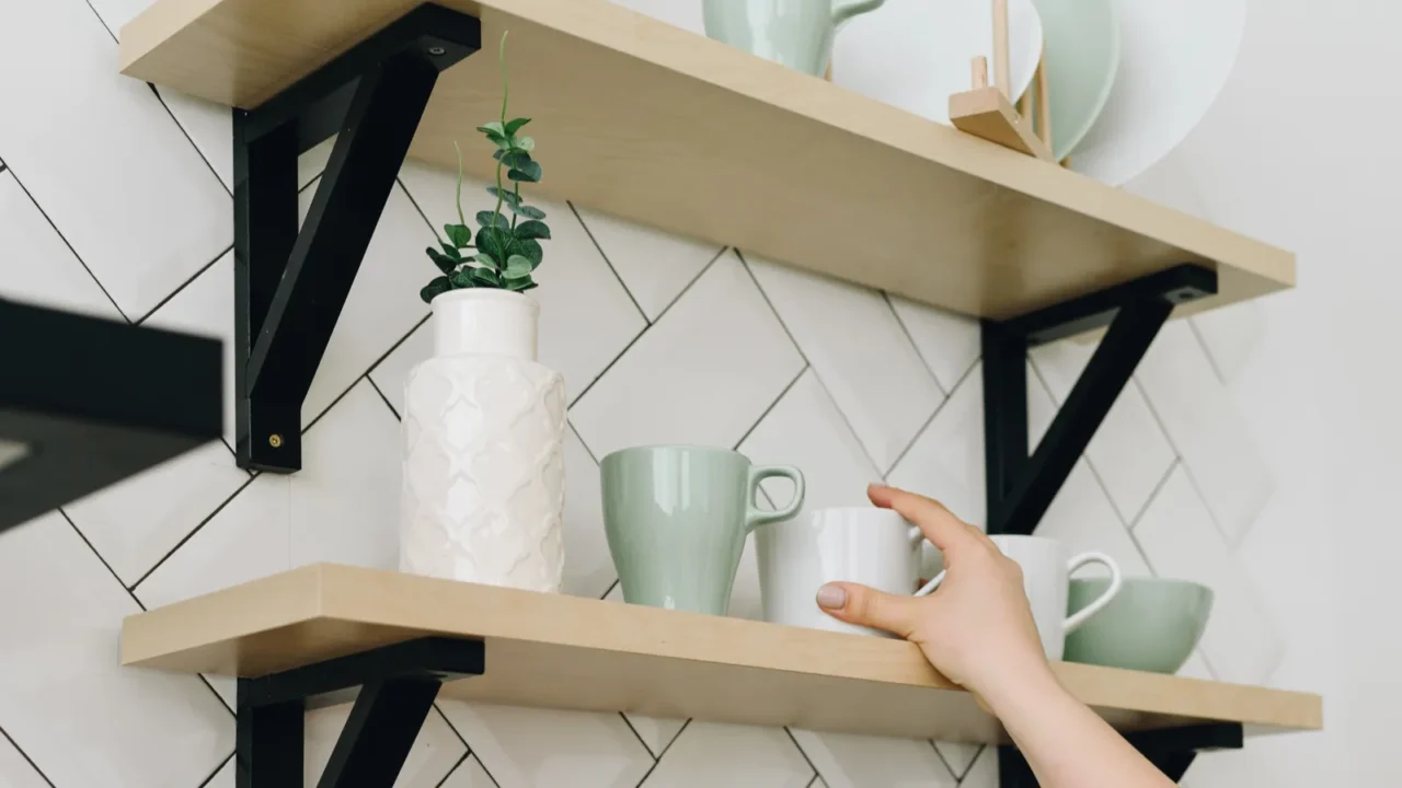 a womans hand taking a cup from a shelf on