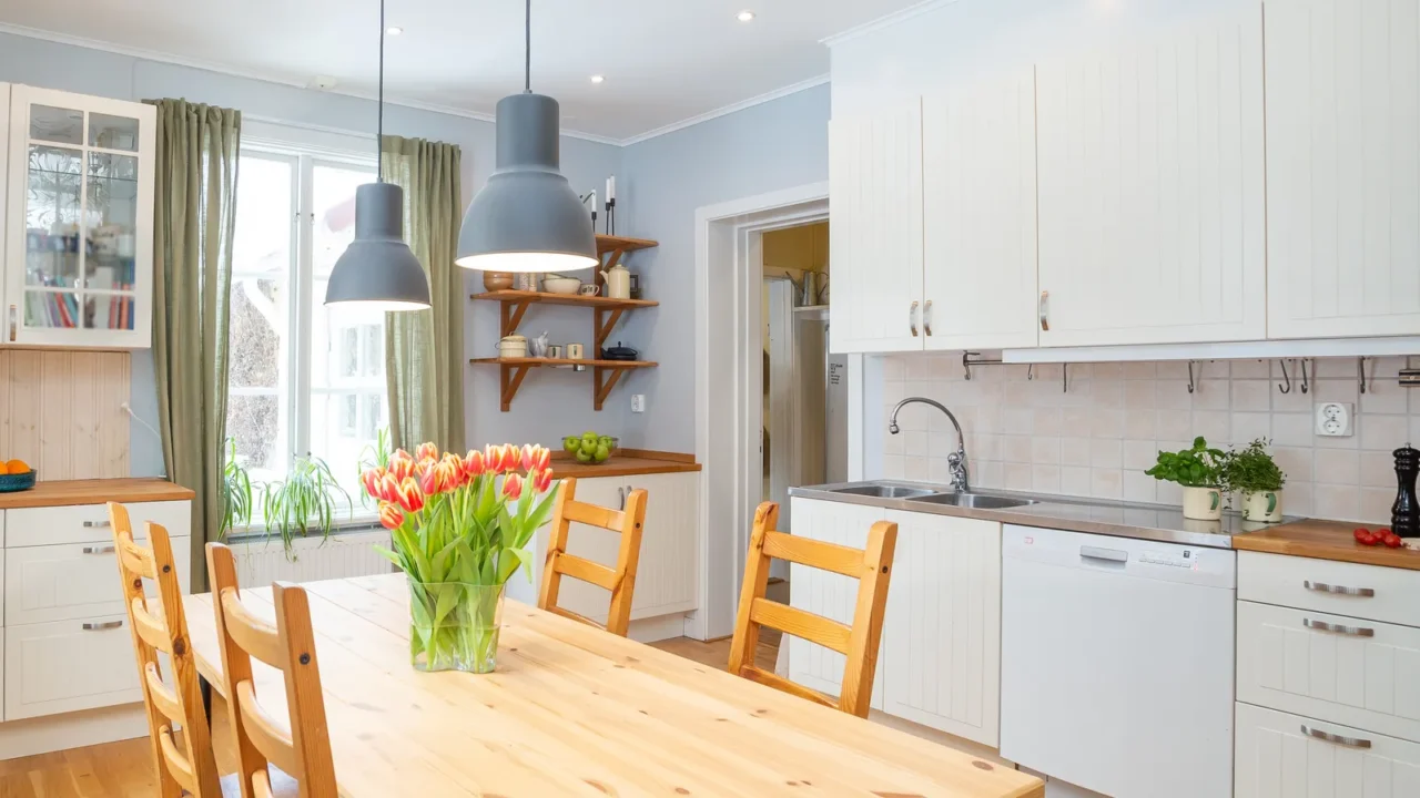 A bright kitchen featuring a wooden dining table and colorful tulips.