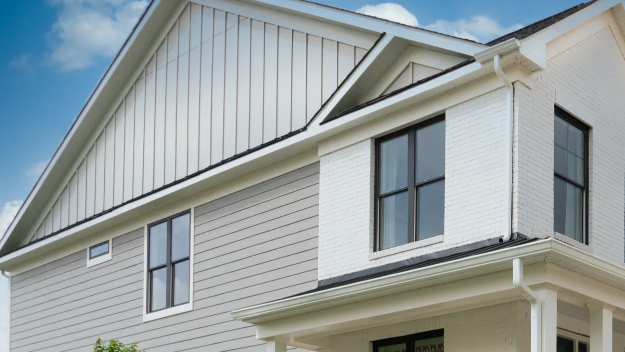 The exterior of a home featuring a mix of siding and brick, with large windows and a contemporary roofline.