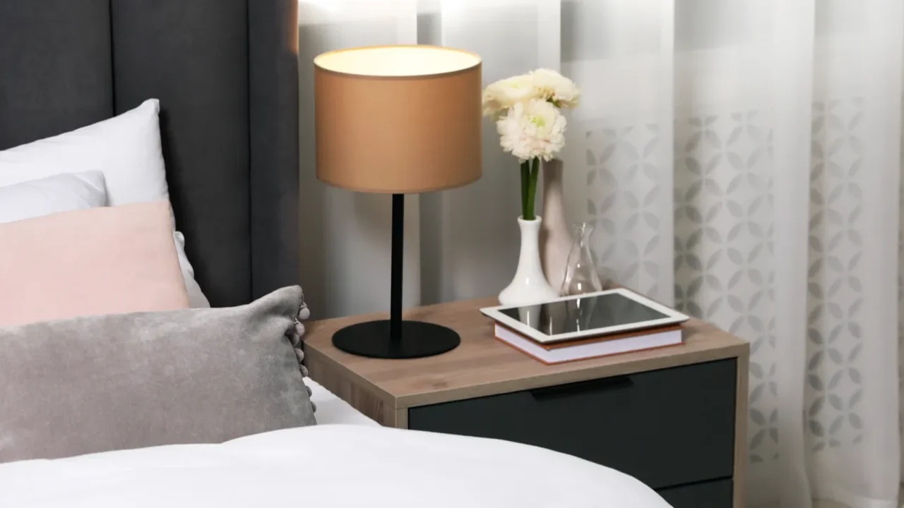 comfortable bed with cushions lamp and different decor on bedside