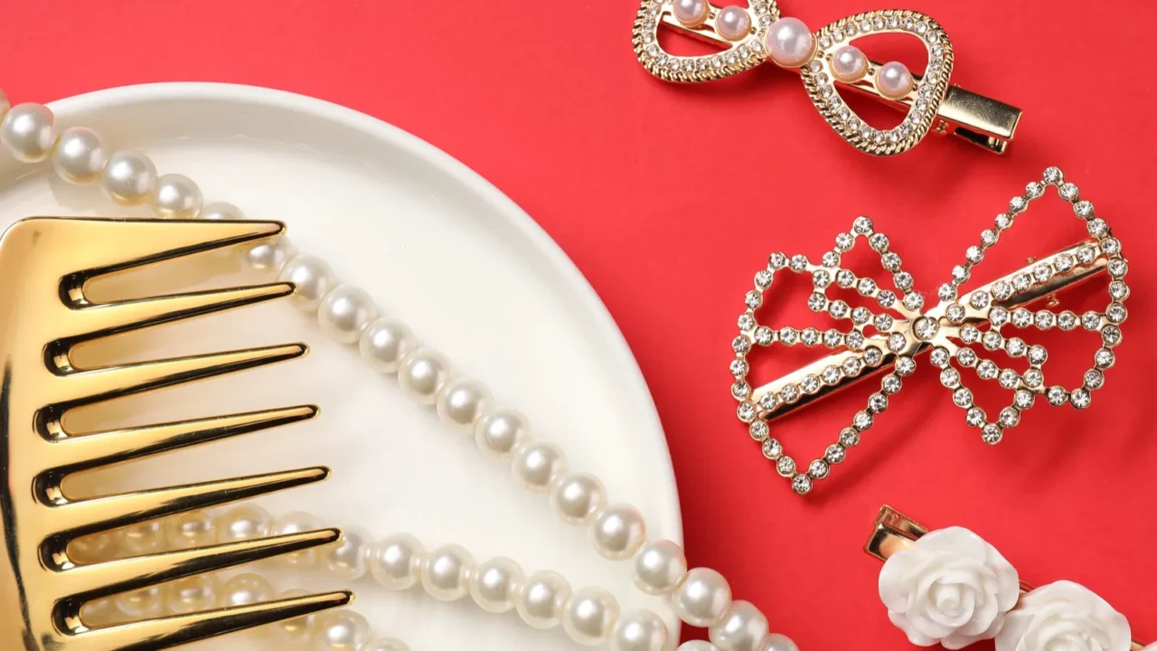 different hair clips pearl necklace and comb on red background