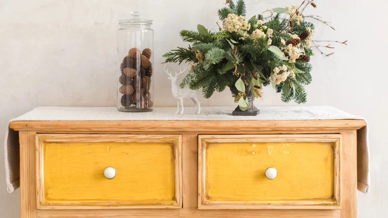dresser with conifer branches and christmas decorations