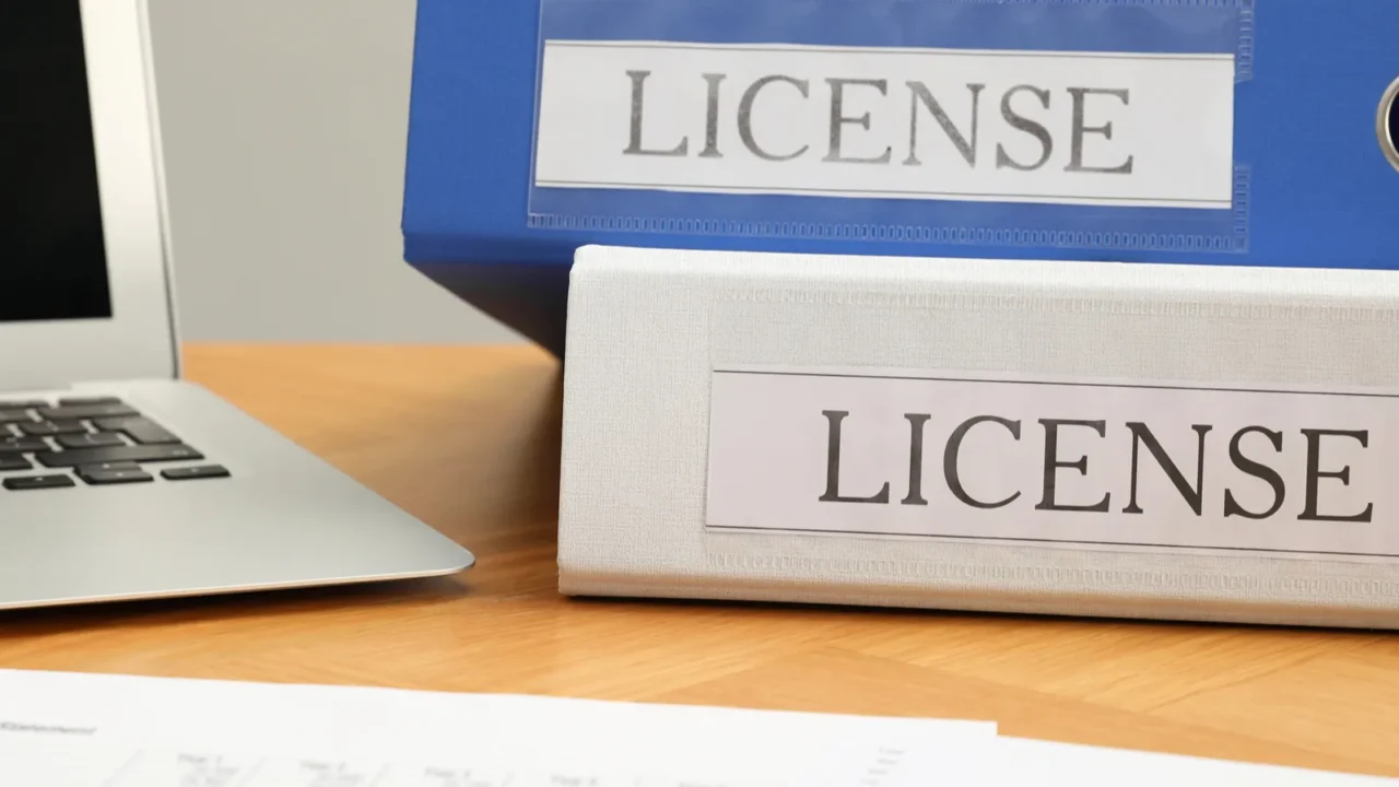 file folders with labels license and laptop on wooden table