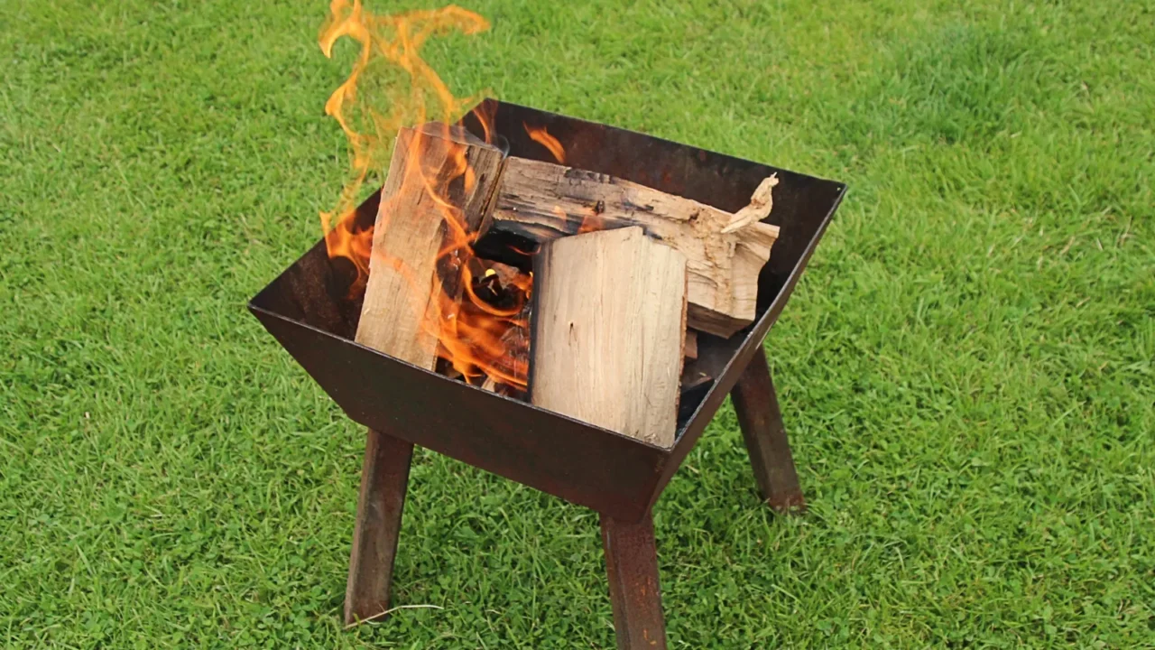 firepit with flames and logs on grass lawn