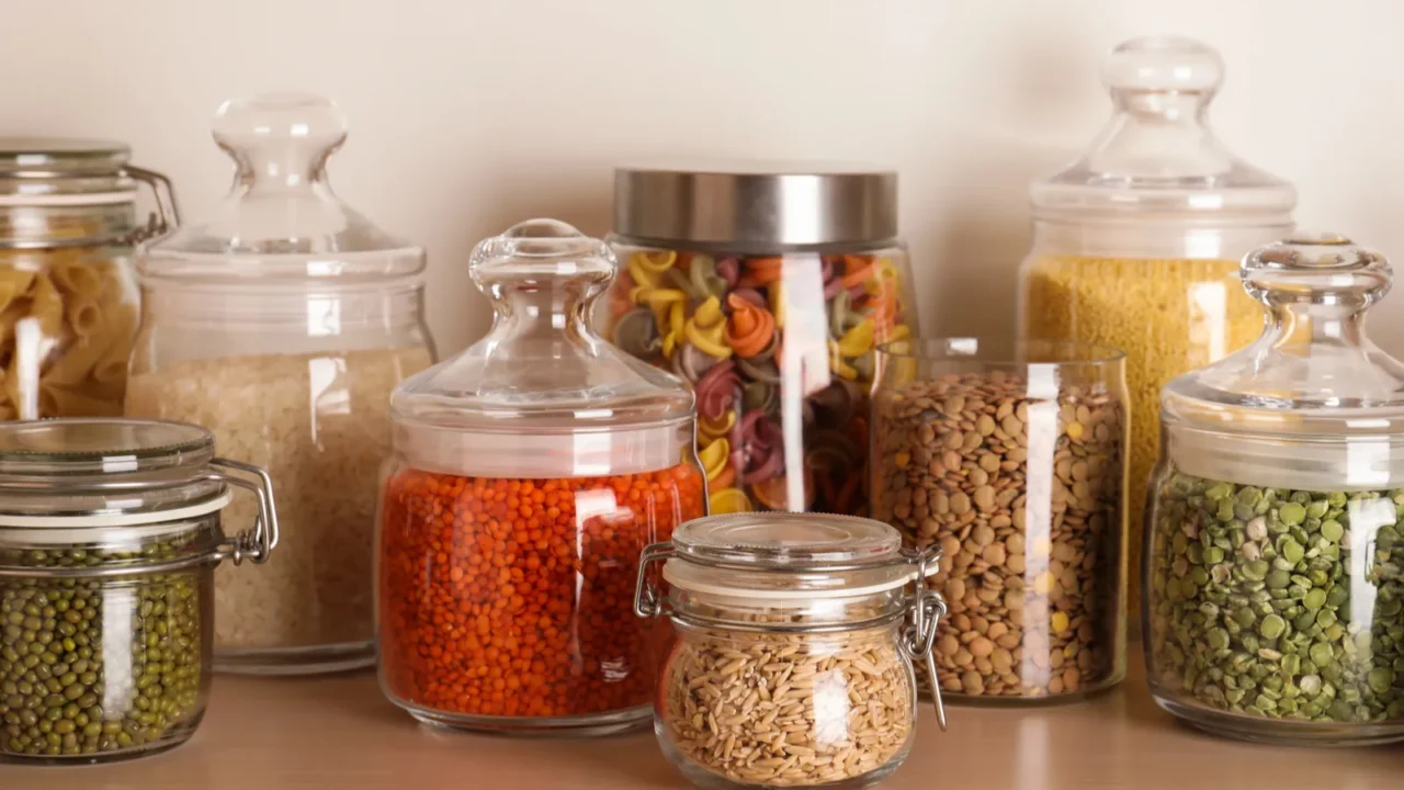 glass jars with different types of groats on wooden shelf