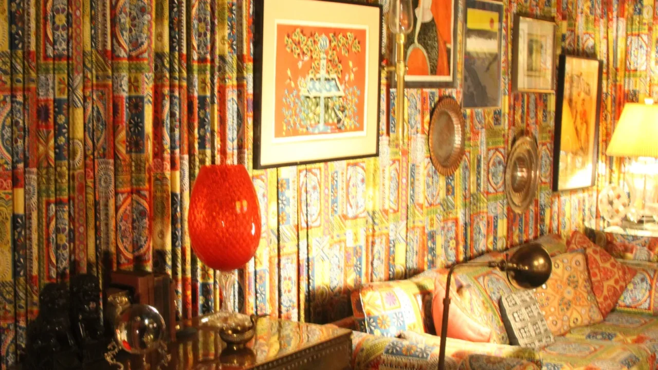 Vibrant, bohemian-style room with colorful patterned walls, eclectic pillows, and lighting.