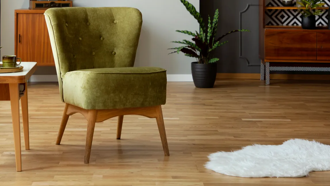 A stylish green armchair with wooden legs in a modern living space.