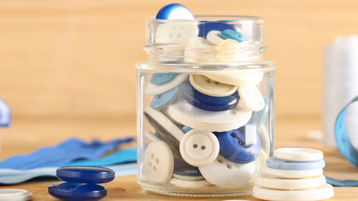 jar of different colorful buttons with supplies and manual sewing