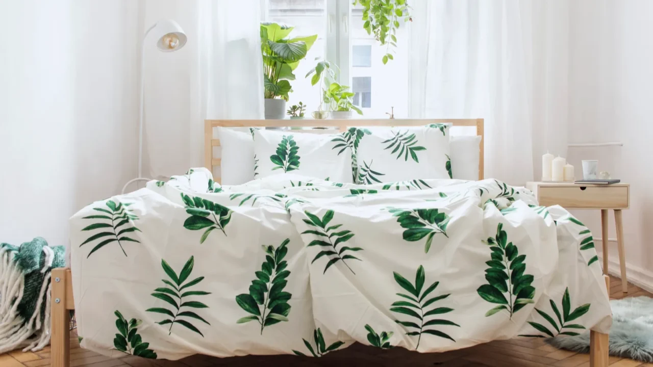 A serene bedroom with leafy bedding and plants, creating a fresh atmosphere.
