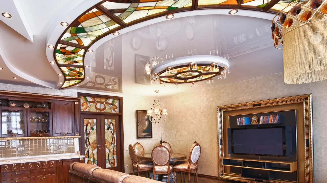 A stylish living room interior with dining table and chairs, TV, wooden cabinets, and chandelier hanging from patterned ceiling.