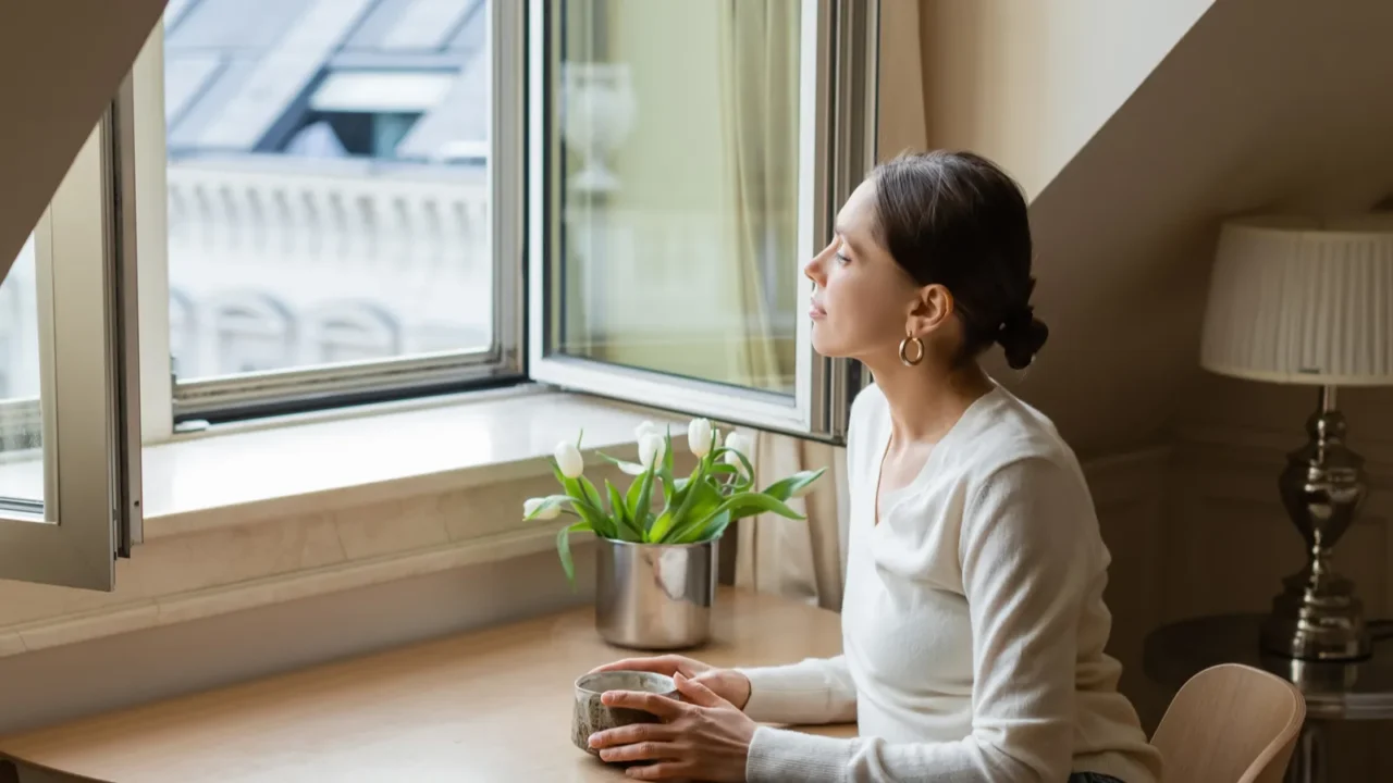 pensive woman sitting with clay cup near tulips and looking