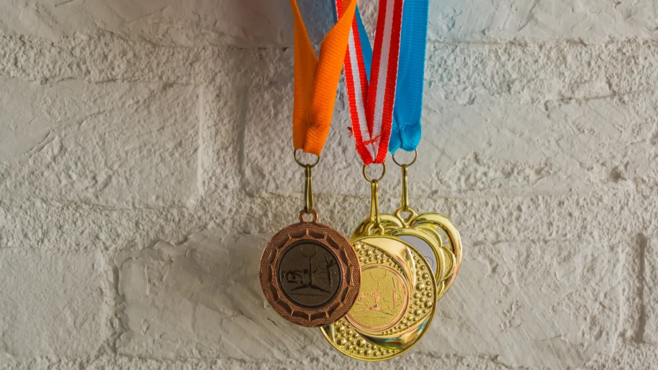 rhythmic gymnastics medals hanging in front of a white brick