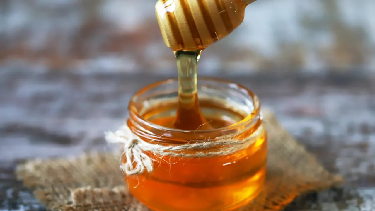 A jar of honey with a honey dipper.