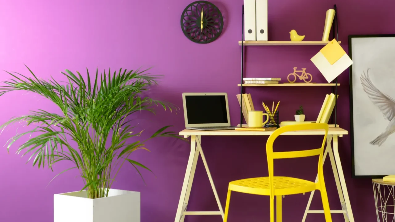 stylish workplace with modern laptop near purple color wall and yellow chair