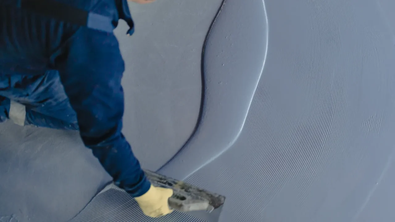 the worker applies gray epoxy resin to the new floor