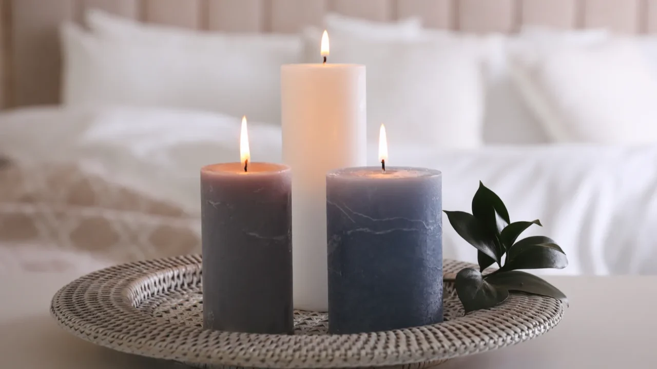 tray with burning candles and leaves on white table indoors