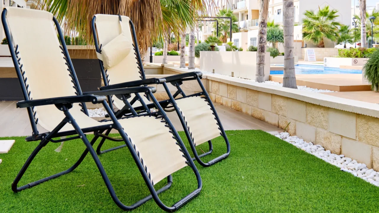 two empty lounge chairs on artificial lawn grass inside of