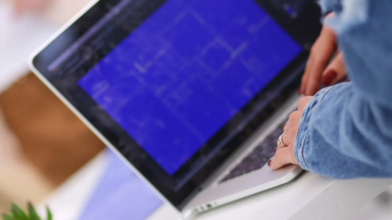 A woman wearing a denim jacket is creating a layout using a software on her laptop.