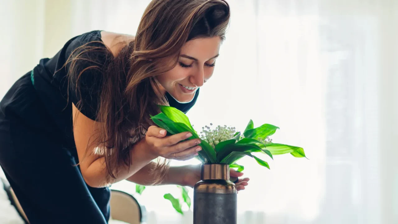 woman smelling flowers in vase on table allergy free housewife