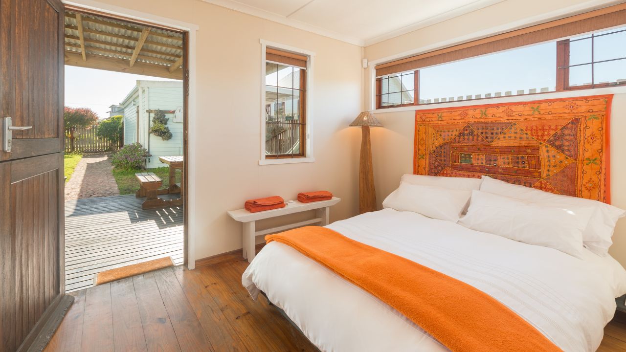 Comfortable bedroom with white bedding, wooden furniture, and outside access.