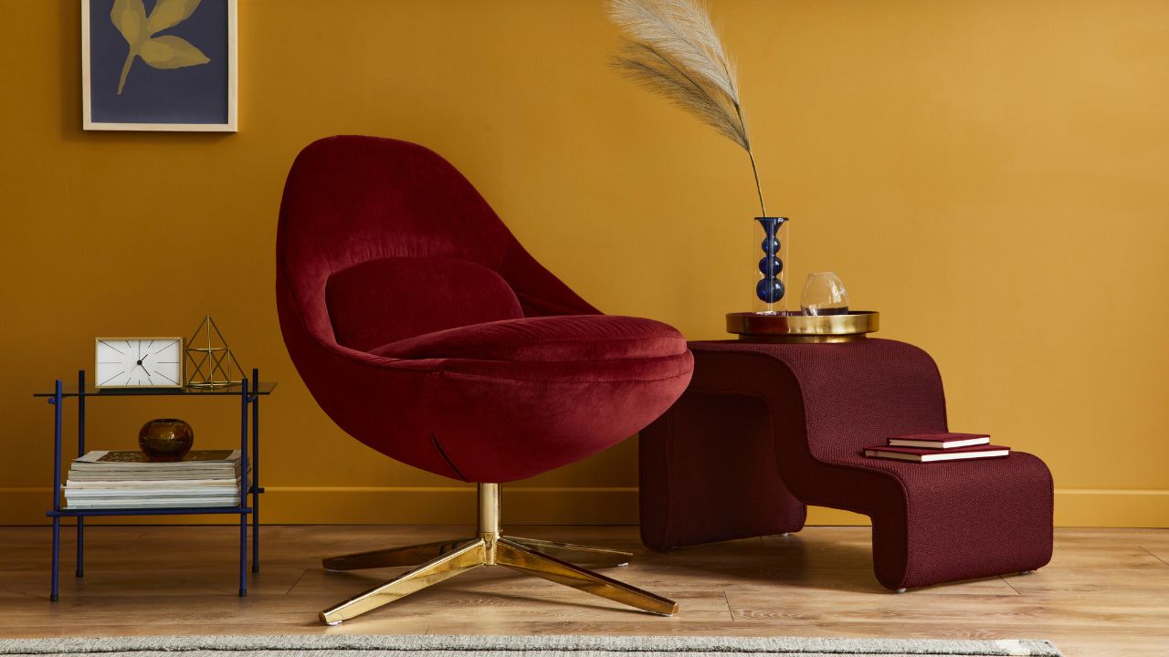 Stylish living area with mustard yellow walls and plush red velvet chair.
