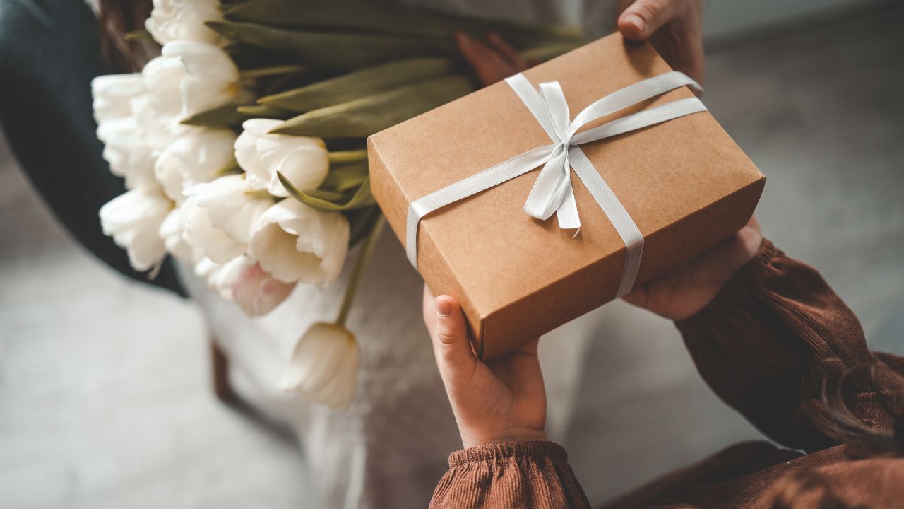 A person receiving a gift box with a bouquet of white tulips.