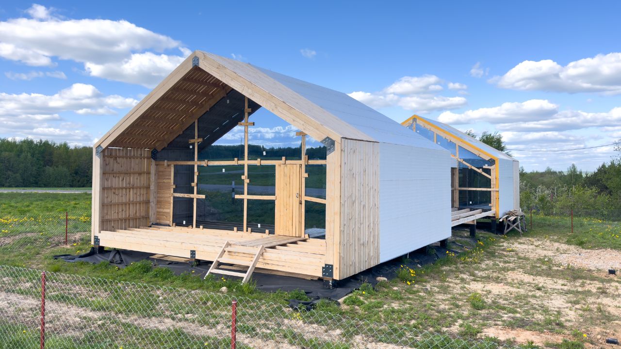 Wooden and barn under-construction shed with black and natural wood exterior on a grassy field.