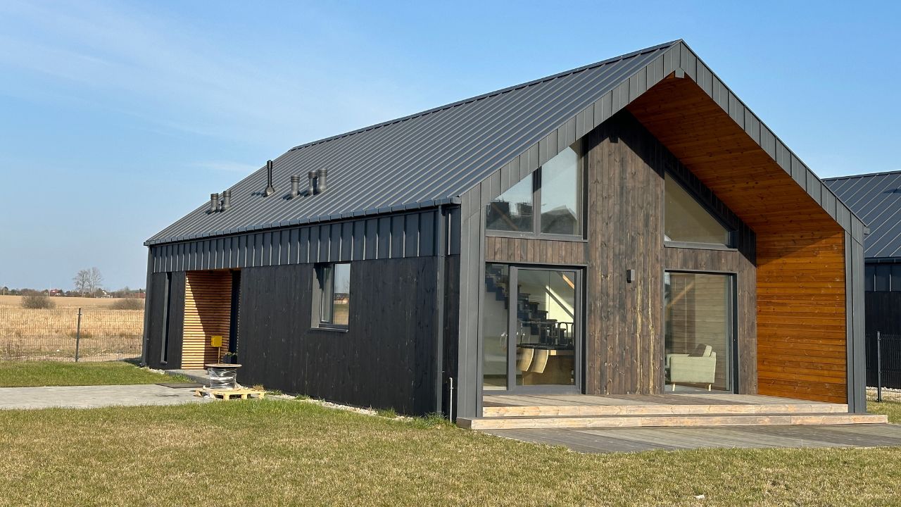 Small wooden barn with a mix of black and natural wood exterior..