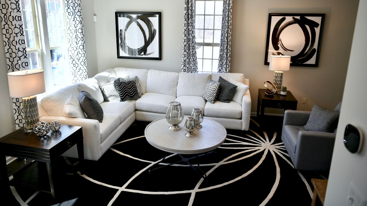Bright living room with a white sofa, black and white curtains, and modern decor, illuminated by natural light.