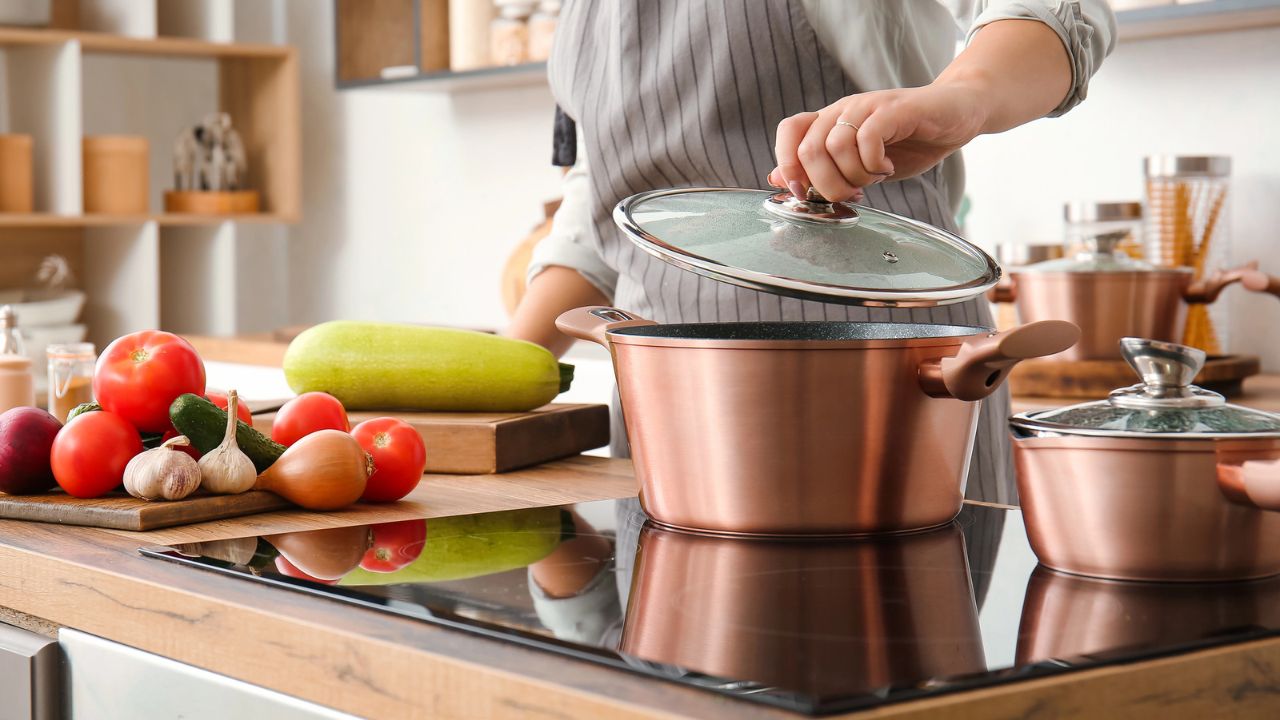A woman cooking food in copper cookware.