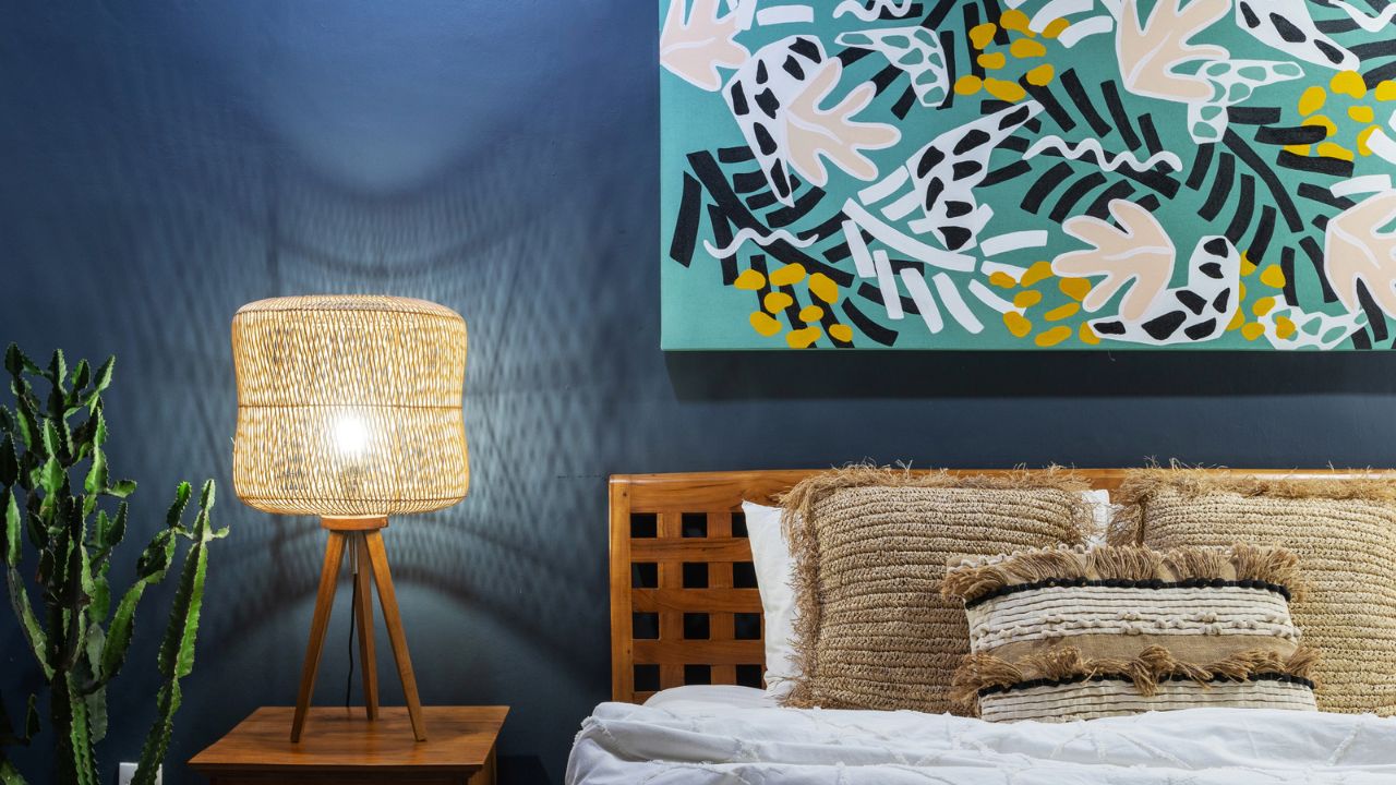 A bedroom with a large wooden bed, round mirror, and a woven rattan pendant light.