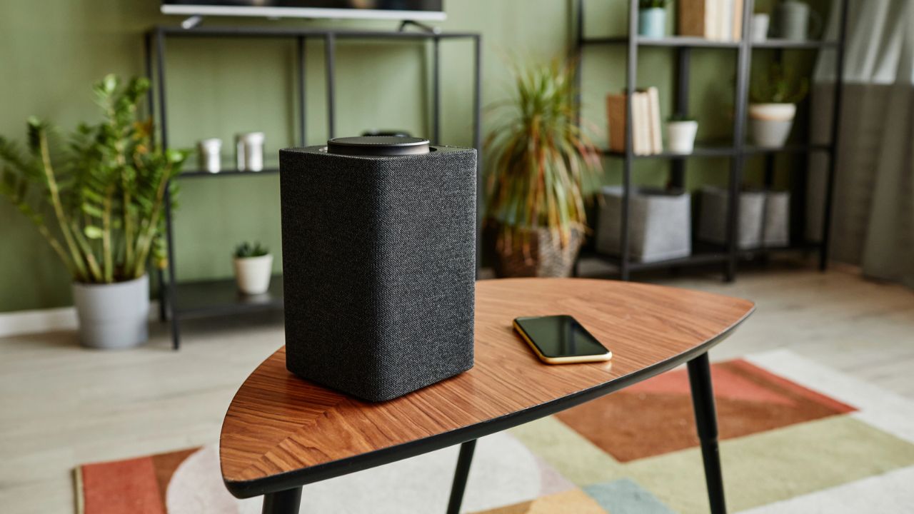 Close-up of a speaker and smartphone on a wooden coffee table.