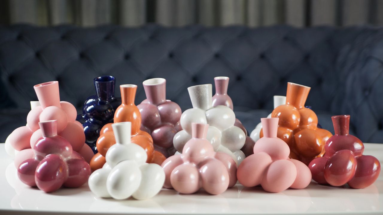 Collection of colorful, modern ceramic vases in shades of pink, white, navy, and orange on a white surface.