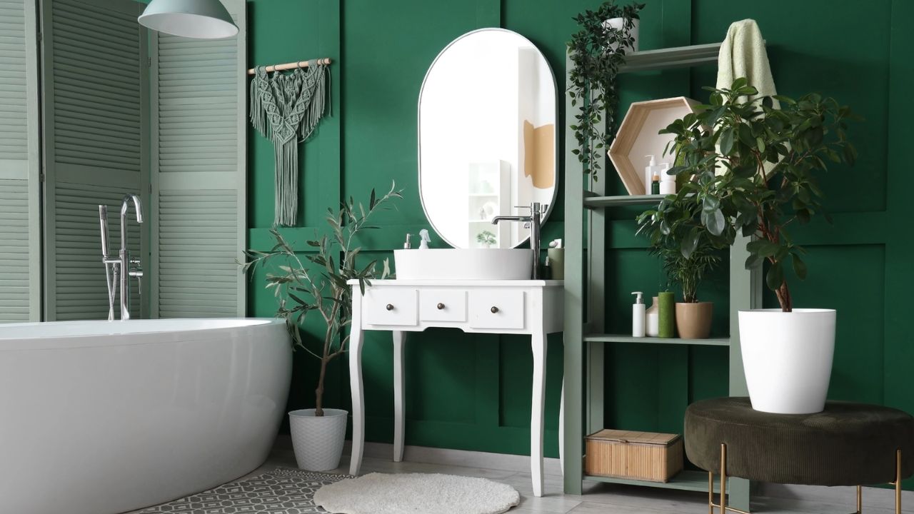 Modern bathroom with green walls, white bathtub, and decorative plants.