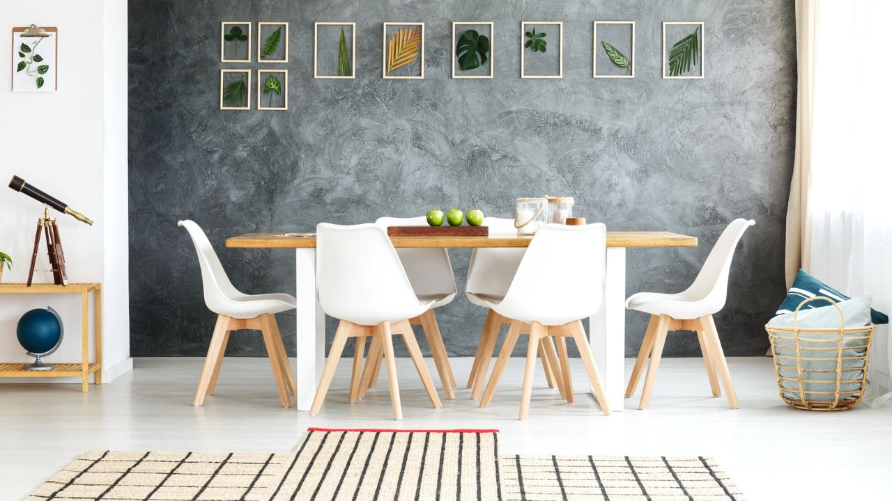 A minimalist dining set with white chairs, wooden table, and framed greenery wall art.