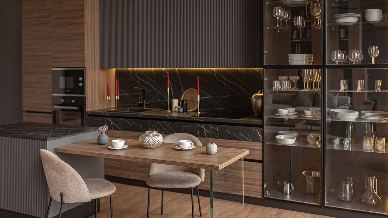 Modern kitchen with dark cabinetry and a marble backsplash, decorated with red candles.