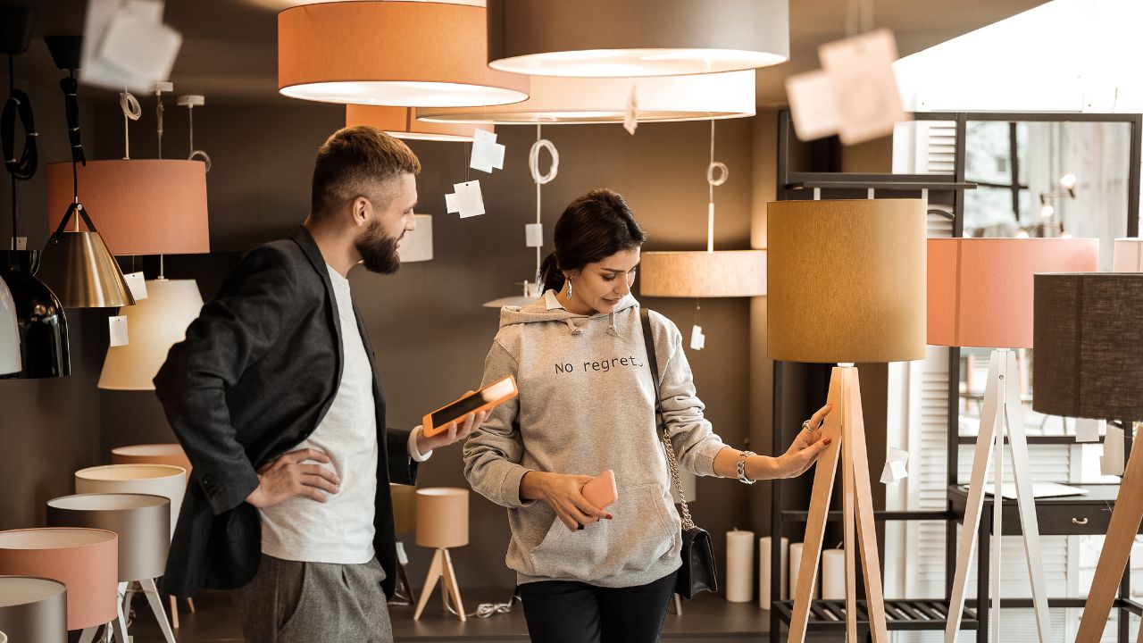 A woman is browsing or selecting table lamps in a lighting store.