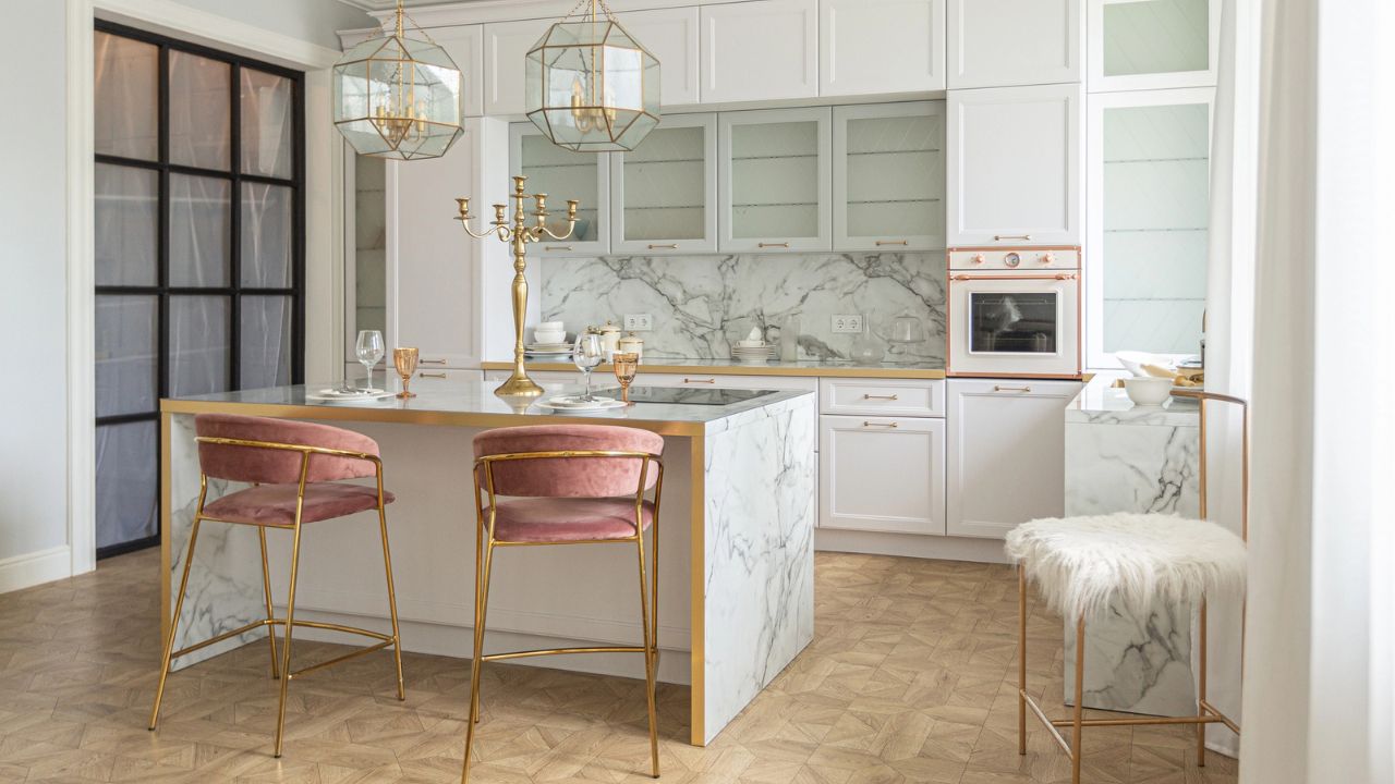 Elegant kitchen with white cabinets, marble backsplash, and gold pendant lights.