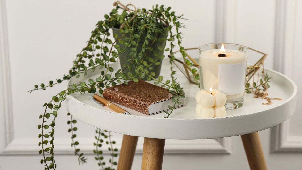 A cozy table with candles, plants, and a notebook.